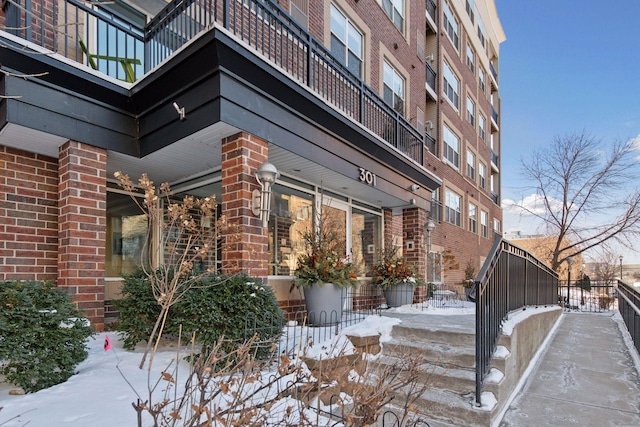 snow covered property featuring brick siding