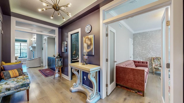 hall with an inviting chandelier, crown molding, and light hardwood / wood-style floors