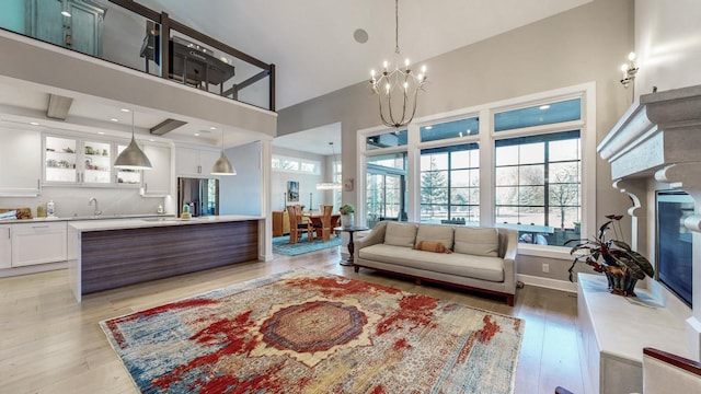 living room with a towering ceiling, a notable chandelier, and light wood-type flooring