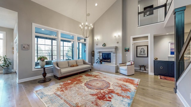 living room featuring an inviting chandelier, light hardwood / wood-style flooring, high vaulted ceiling, and a healthy amount of sunlight