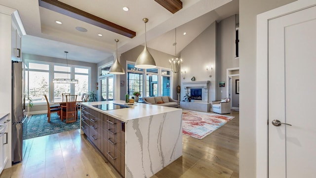 kitchen with hanging light fixtures, white cabinetry, a kitchen island, and black electric cooktop