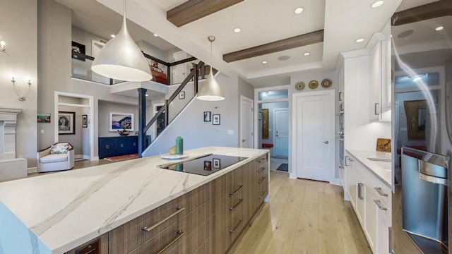 kitchen with pendant lighting, white cabinets, black electric cooktop, a center island, and beam ceiling