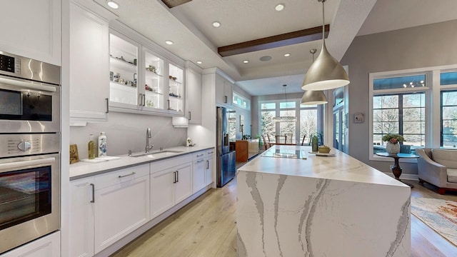 kitchen featuring pendant lighting, double oven, sink, white cabinets, and fridge with ice dispenser