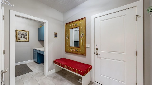 doorway to outside with a textured ceiling and light tile patterned flooring