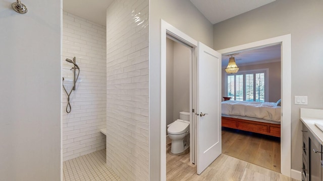 bathroom with hardwood / wood-style flooring, vanity, toilet, and a tile shower