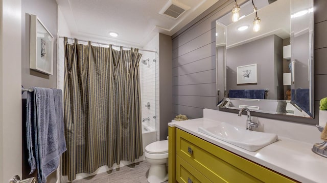 full bathroom with wood walls, vanity, shower / tub combo, and toilet