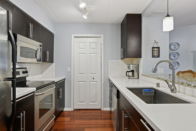 kitchen with dark wood-style floors, a sink, light countertops, appliances with stainless steel finishes, and pendant lighting