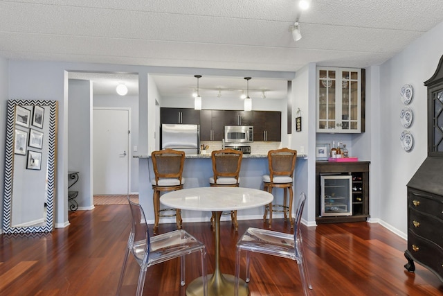 dining space with dark wood finished floors, a dry bar, baseboards, and wine cooler