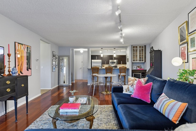 living room with baseboards, a textured ceiling, wood finished floors, and rail lighting