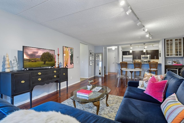 living area featuring a textured ceiling, baseboards, and wood finished floors