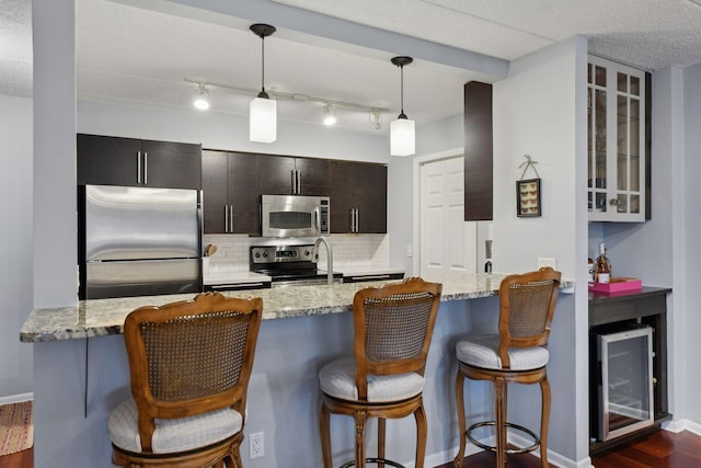 kitchen with tasteful backsplash, hanging light fixtures, appliances with stainless steel finishes, and light stone counters