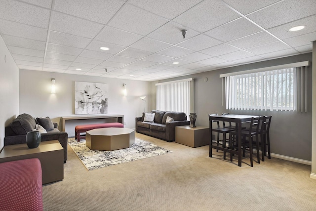 carpeted living area with a drop ceiling, recessed lighting, and baseboards