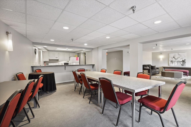 dining room featuring light carpet, a drop ceiling, and recessed lighting