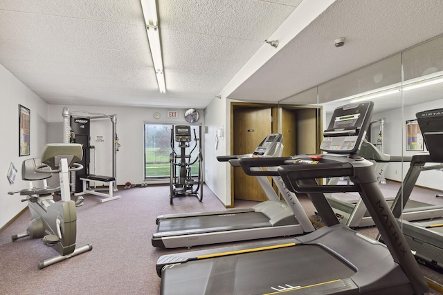 exercise room with a textured ceiling and baseboards