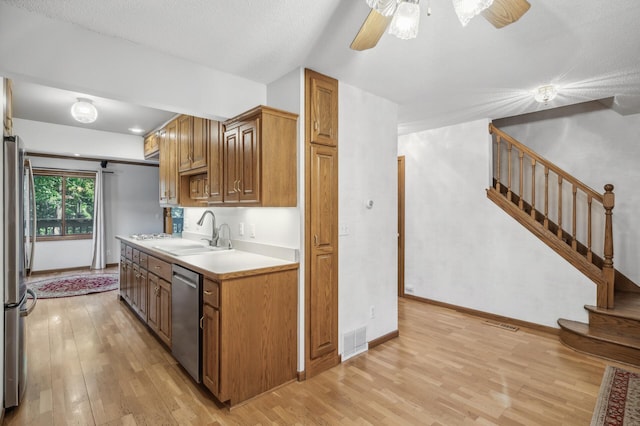 kitchen featuring stainless steel appliances, sink, a textured ceiling, and light wood-type flooring