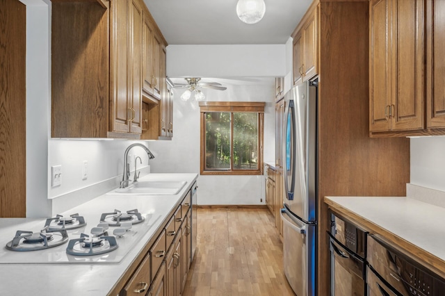 kitchen with sink, white gas cooktop, light wood-type flooring, stainless steel fridge, and ceiling fan