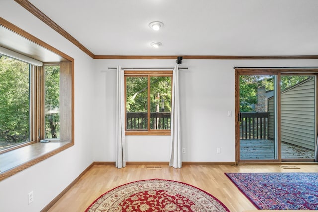 unfurnished room with crown molding, wood-type flooring, and a wealth of natural light