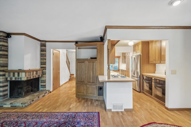 kitchen featuring a brick fireplace, black oven, stainless steel refrigerator, and white gas cooktop