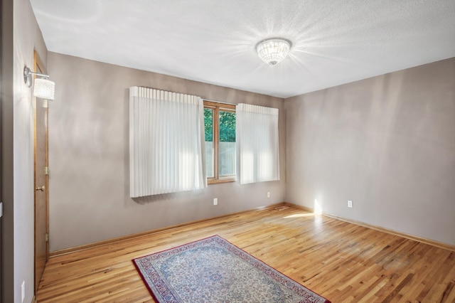 spare room featuring light hardwood / wood-style floors and a textured ceiling