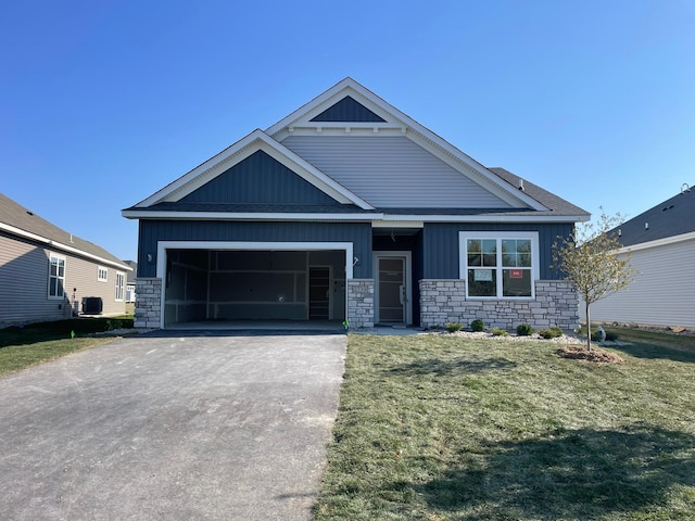 craftsman-style home with a garage, a front yard, and central AC unit