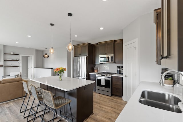 kitchen featuring sink, a breakfast bar area, dark brown cabinets, pendant lighting, and stainless steel appliances