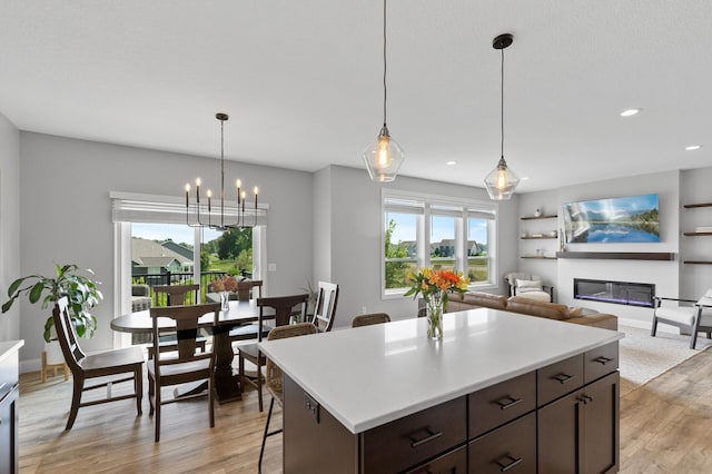 kitchen with pendant lighting, light hardwood / wood-style flooring, a breakfast bar area, dark brown cabinets, and a center island