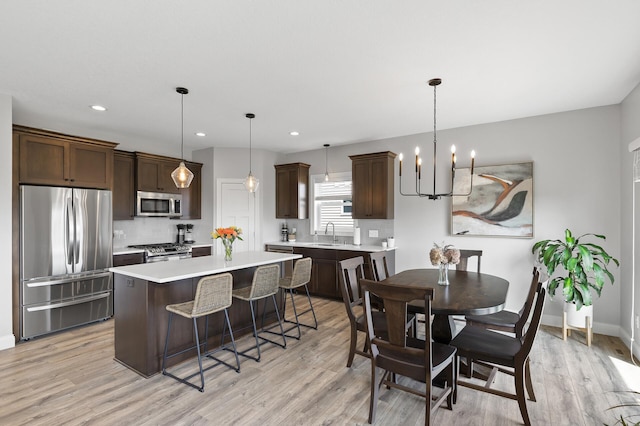 kitchen featuring decorative light fixtures, tasteful backsplash, sink, a center island, and stainless steel appliances