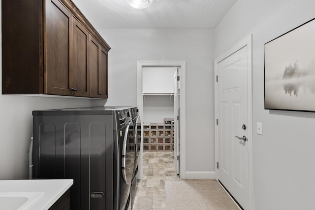 laundry room with separate washer and dryer, cabinets, and a textured ceiling