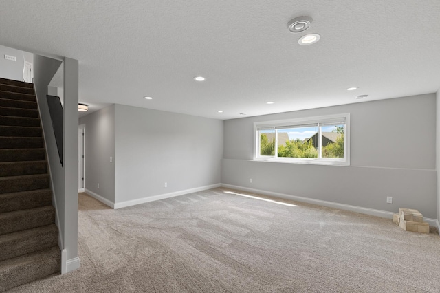 spare room with light carpet and a textured ceiling