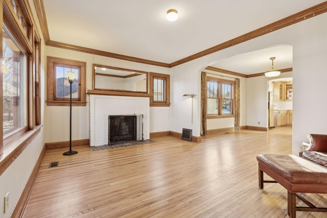 living room with ornamental molding, plenty of natural light, a fireplace, and light hardwood / wood-style floors