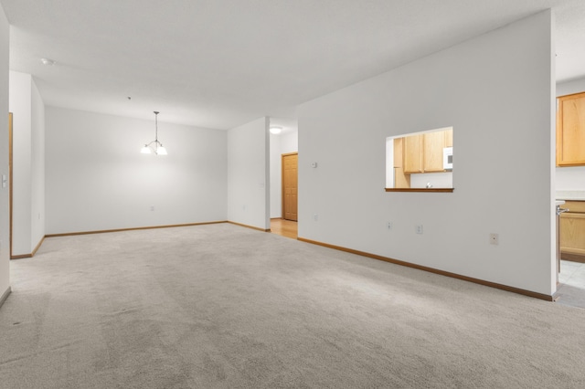 unfurnished living room with light colored carpet and a chandelier