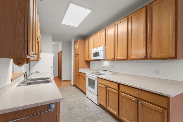 kitchen featuring white appliances, a skylight, and sink