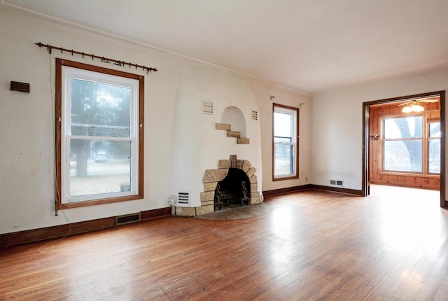 unfurnished living room with hardwood / wood-style flooring and a stone fireplace