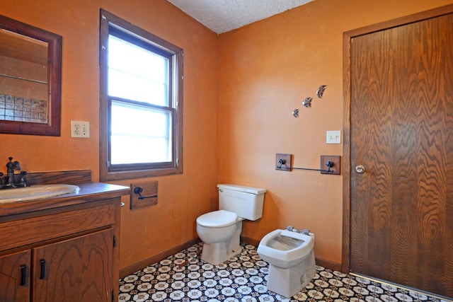 bathroom featuring a bidet, vanity, a textured ceiling, and toilet