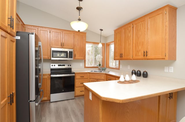 kitchen featuring lofted ceiling, sink, kitchen peninsula, pendant lighting, and stainless steel appliances