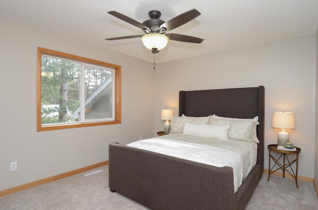 carpeted bedroom featuring ceiling fan and a textured ceiling