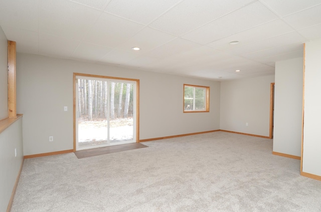 carpeted empty room featuring a drop ceiling