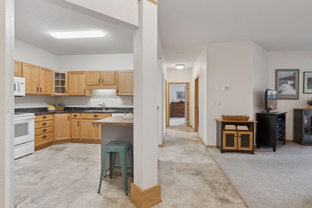 kitchen featuring sink, white appliances, a breakfast bar area, light colored carpet, and light brown cabinets