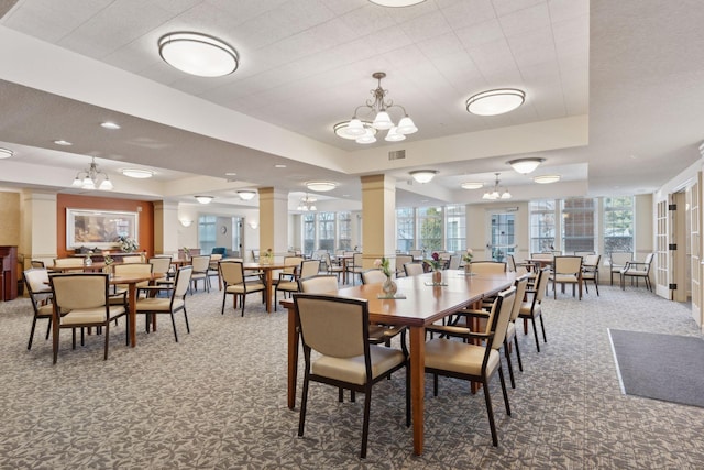 dining area featuring carpet flooring, a tray ceiling, a chandelier, and ornate columns