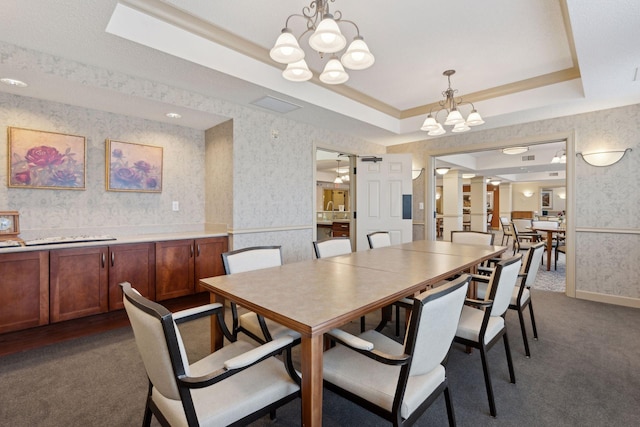 carpeted dining area featuring an inviting chandelier and a tray ceiling