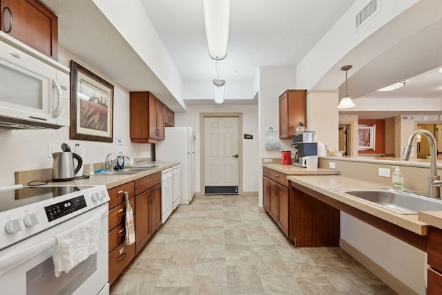 kitchen with hanging light fixtures, sink, and white appliances