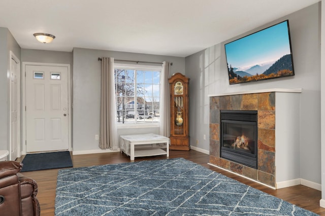 living room featuring a tile fireplace and dark wood-type flooring