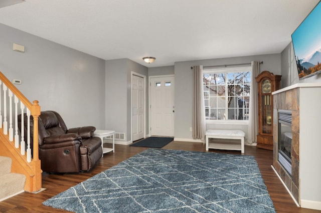 entryway with dark hardwood / wood-style flooring and a tiled fireplace