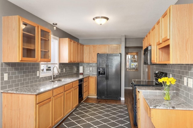 kitchen featuring tasteful backsplash, sink, light stone counters, black appliances, and dark wood-type flooring