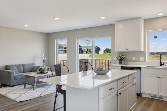 kitchen with white cabinetry, sink, a kitchen breakfast bar, a center island, and stainless steel dishwasher