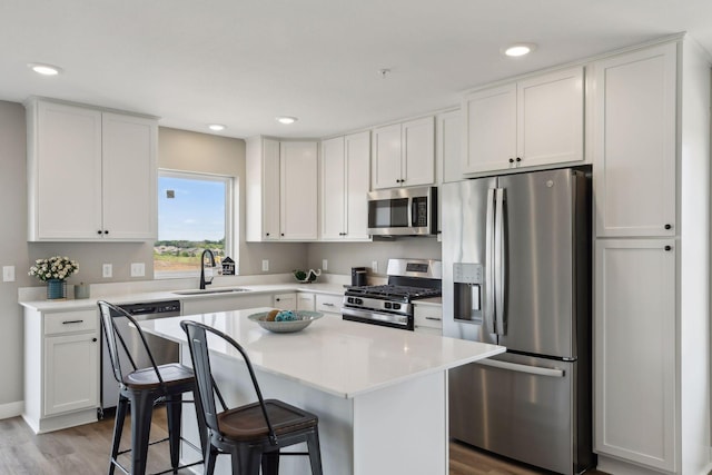 kitchen with stainless steel appliances, a breakfast bar, sink, and a kitchen island