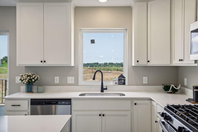 kitchen featuring stainless steel dishwasher, sink, and white cabinets