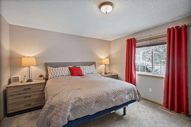 bedroom with carpet floors, visible vents, a textured ceiling, and baseboards