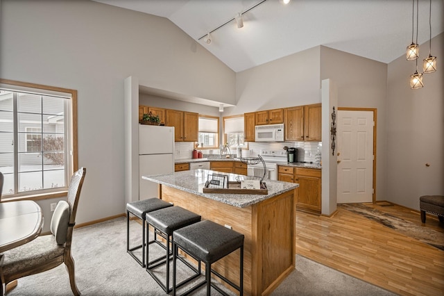 kitchen featuring white appliances, high vaulted ceiling, a center island, and brown cabinetry