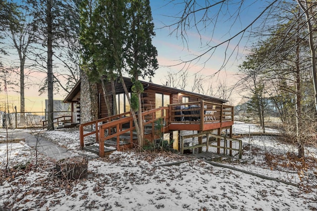 snow covered house with a wooden deck